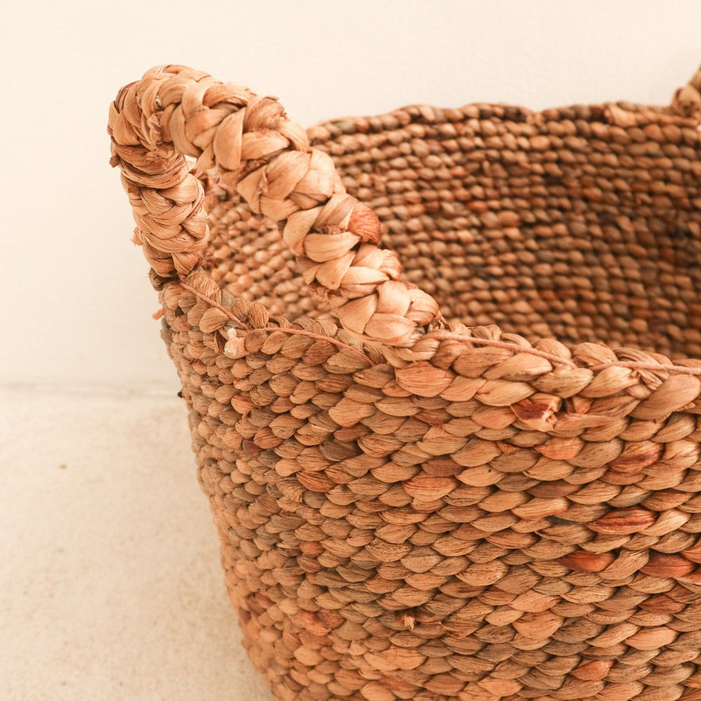 Close-up of a woven basket with a braided handle on a light background