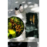 Salad with chickpeas and broccoli on a marble surface with cutlery and salt and pepper shakers.